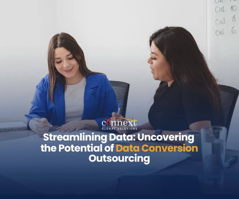 Streamlining-data-uncovering-the-potential-of-data-conversion-outsourcing-two-woman-sitting-at-desk-with-laptops-in-office