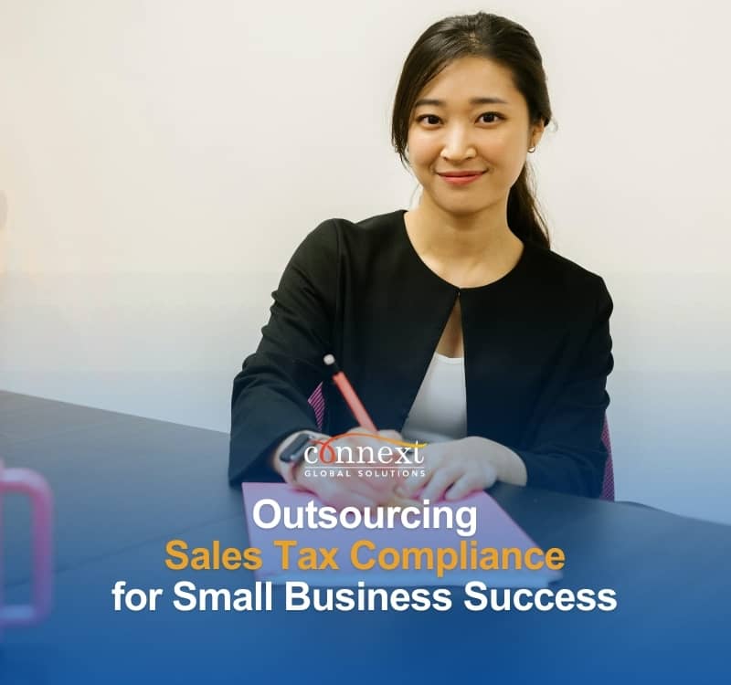 outsourcing-Sales-Tax-Compliance-for-Small-Business-Success-a-smiling-asian-woman-in-corporate-attire-behind-a-desk-in-office